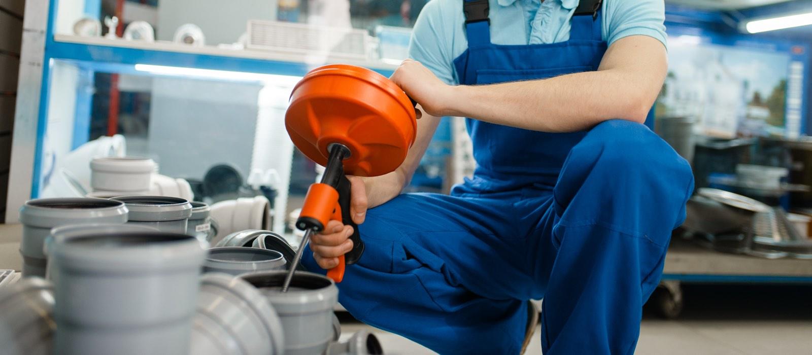 Kneeling man wearing overalls mixing construction materials in bucket