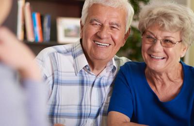 Elderly man and woman smiling at blurry man in foreground